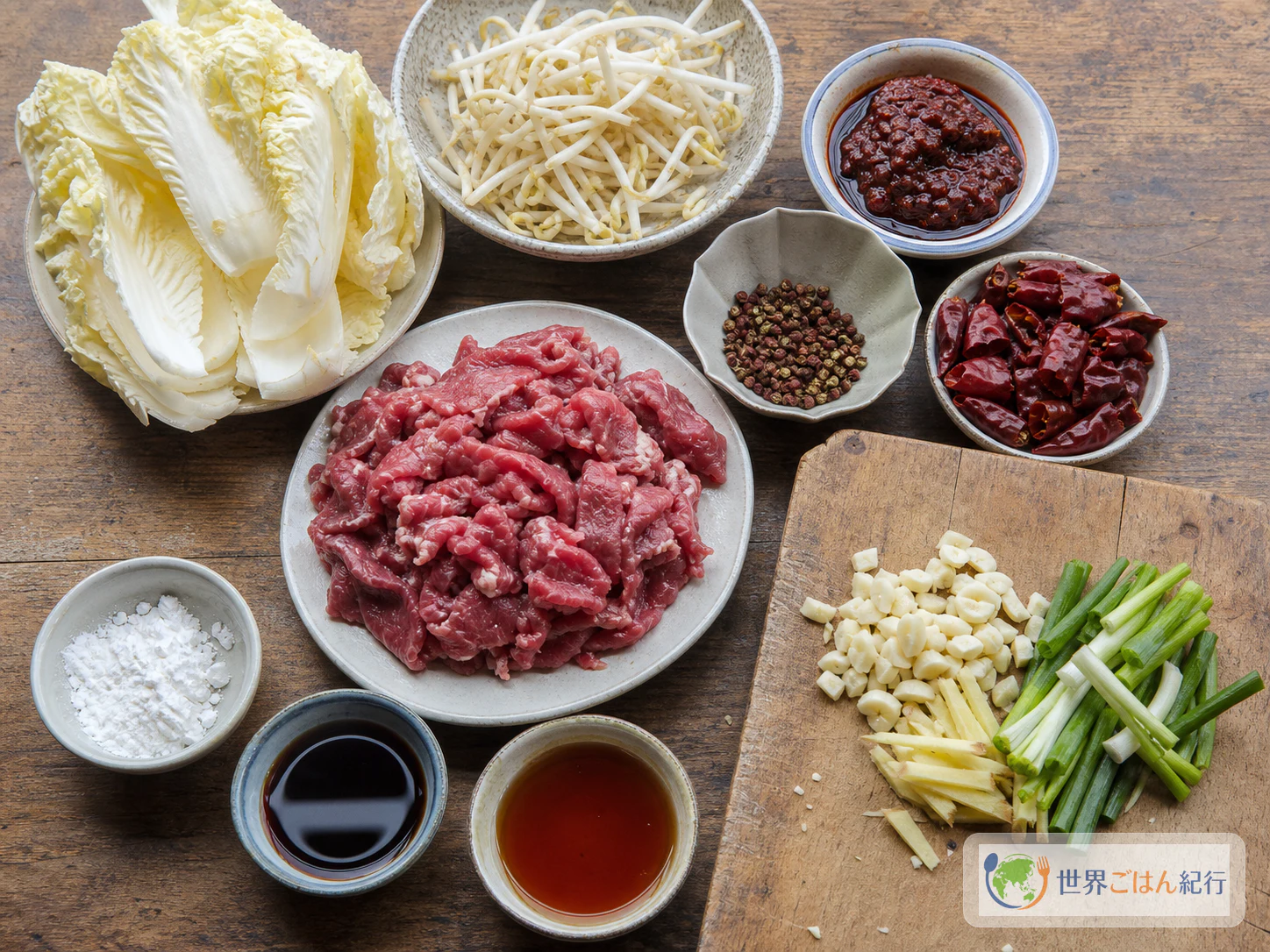 牛薄切り肉、白菜、もやし、豆板醤、花椒、唐辛子、香味野菜を並べた水煮牛肉の材料
