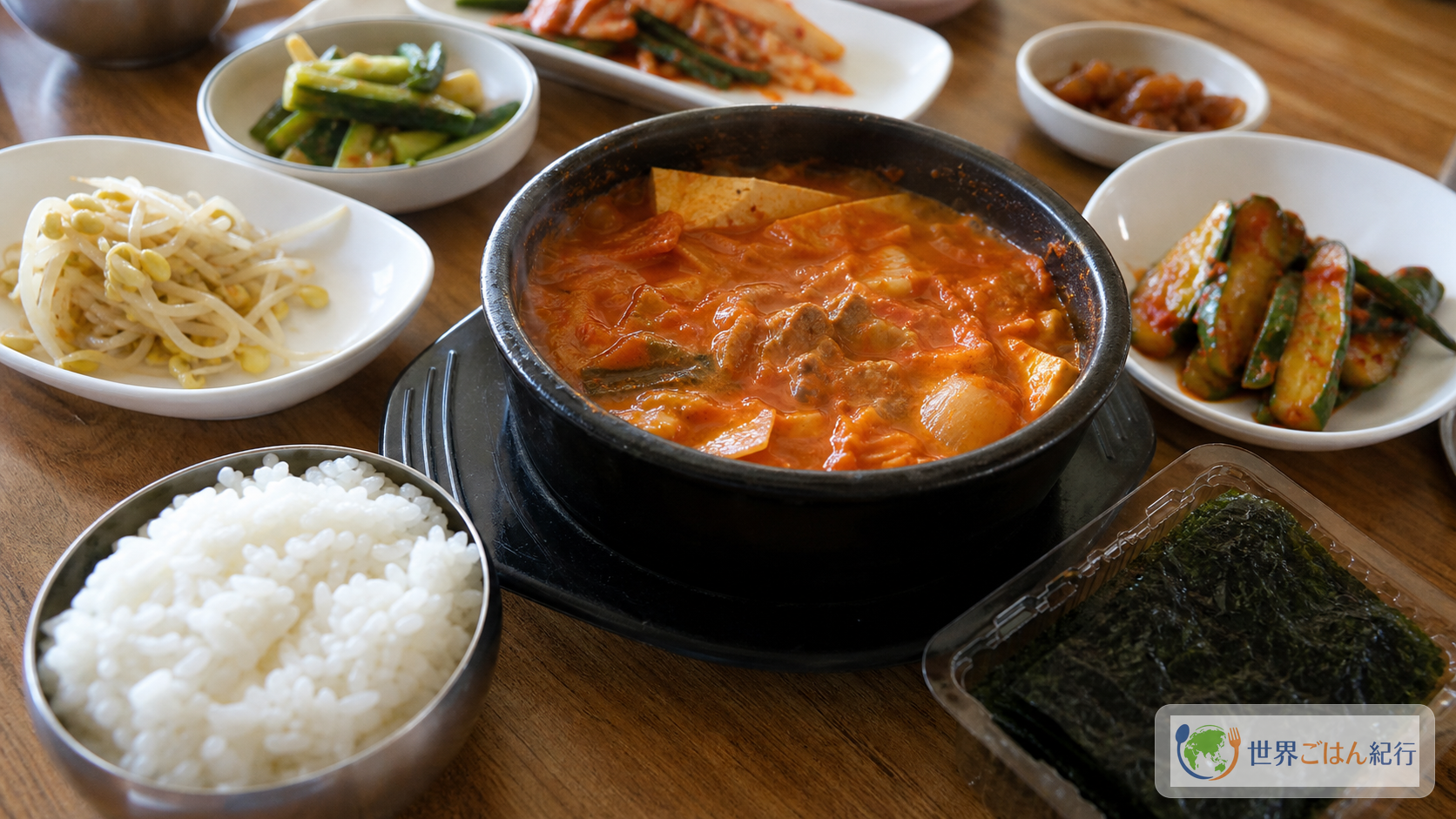キムチチゲ、白ご飯、海苔、ナムル、きゅうりを並べた韓国の家庭食卓