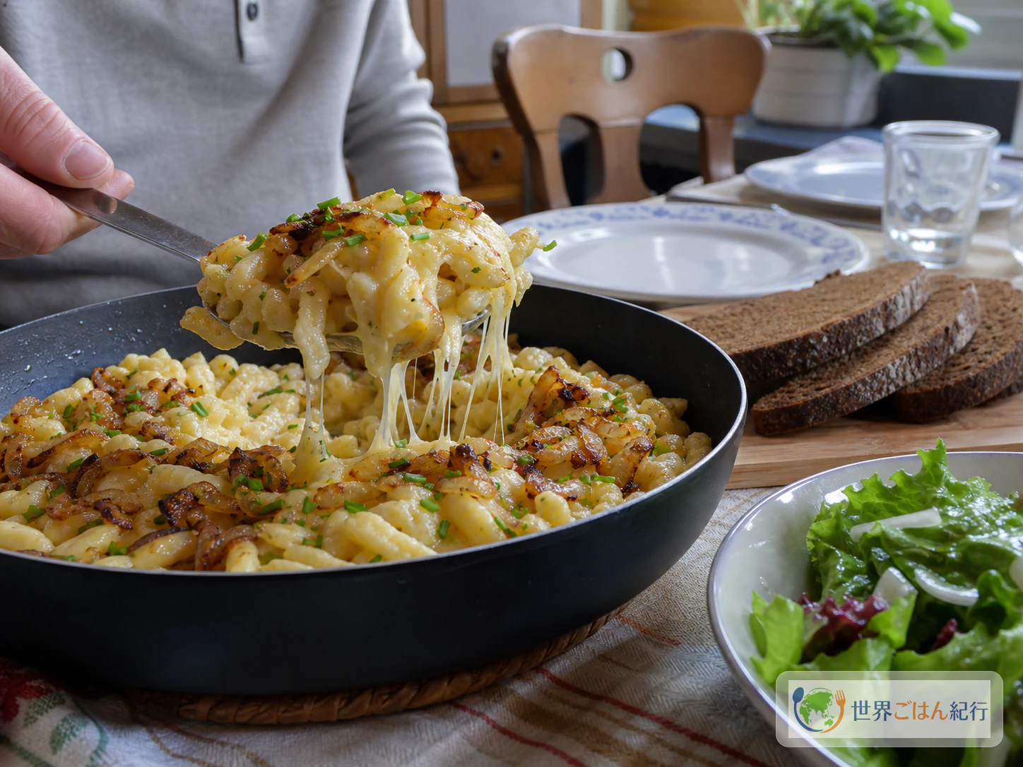 ケーゼシュペッツレをスキレットから取り分け、葉野菜のサラダと黒パンを添えた食卓