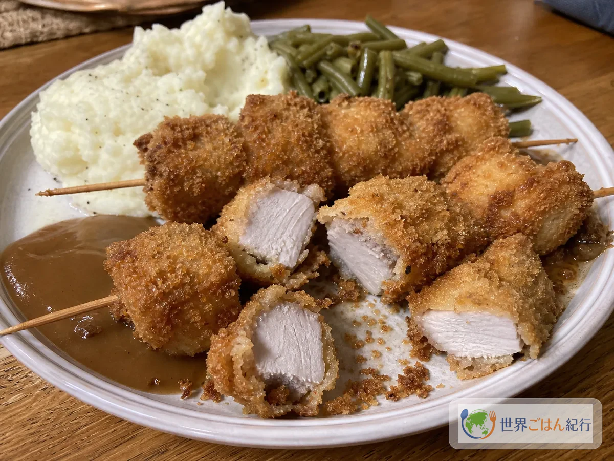 切り口を見せたシティチキンをマッシュポテト、いんげん、グレイビーで盛った皿