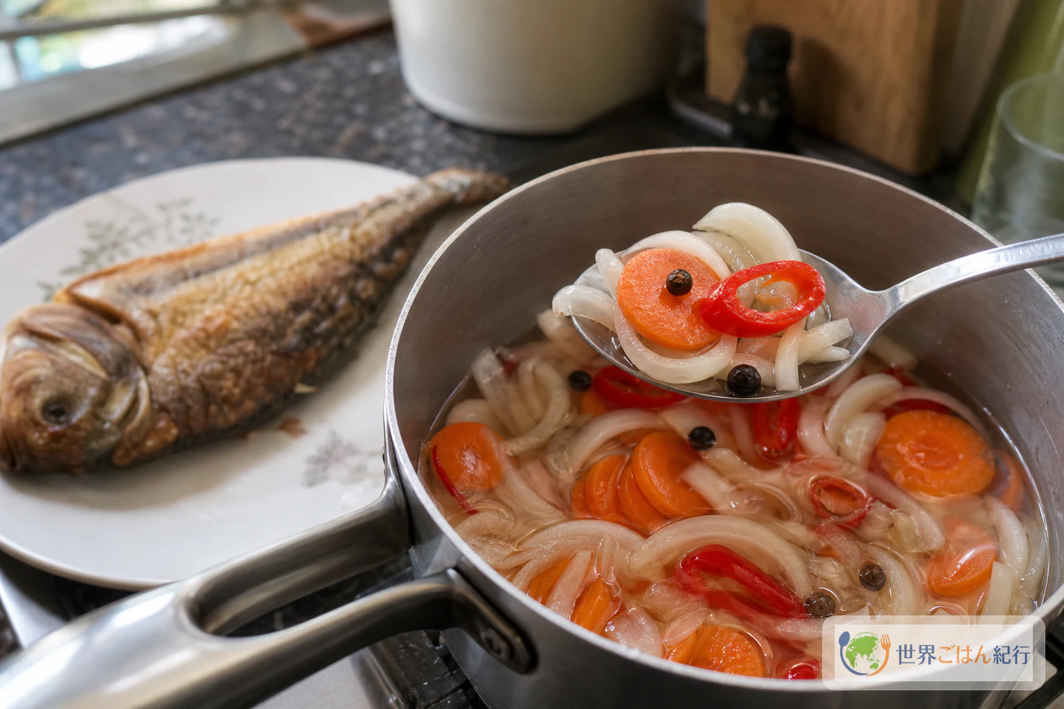 小鍋から赤い唐辛子と酢漬け野菜をすくい、魚の上へかける仕上げの様子