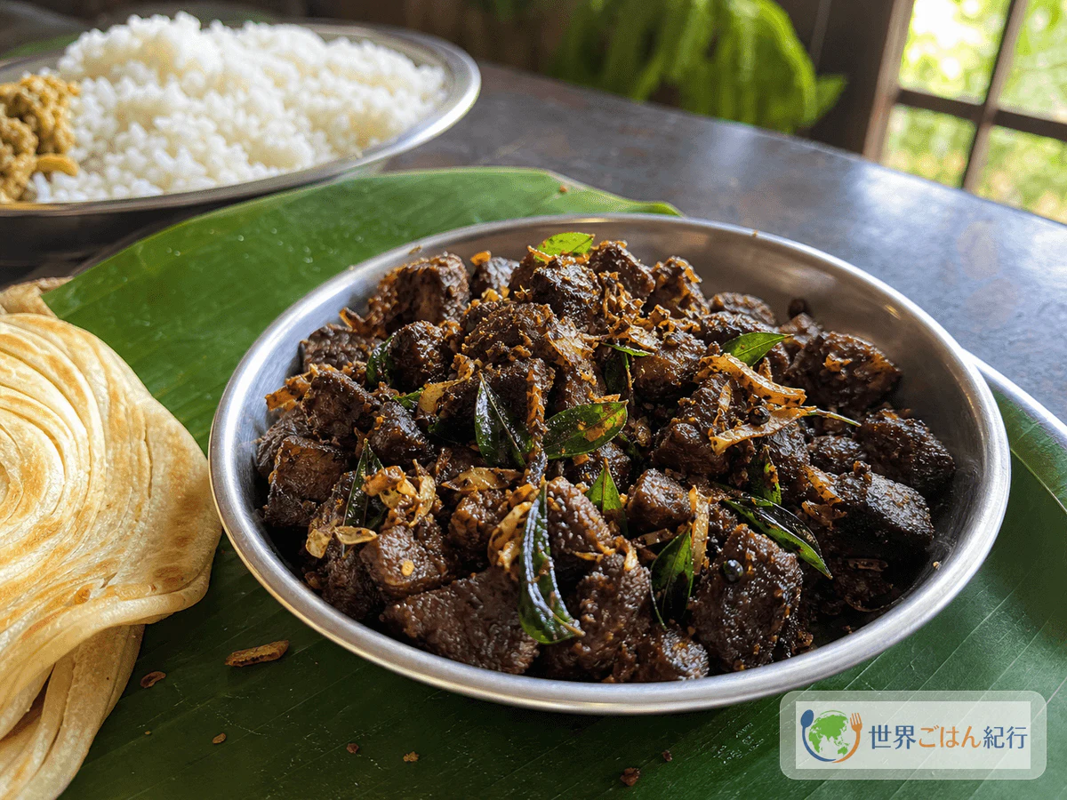 カレーリーフとココナッツをまとったケララビーフフライをパロッタと米に添えた食卓