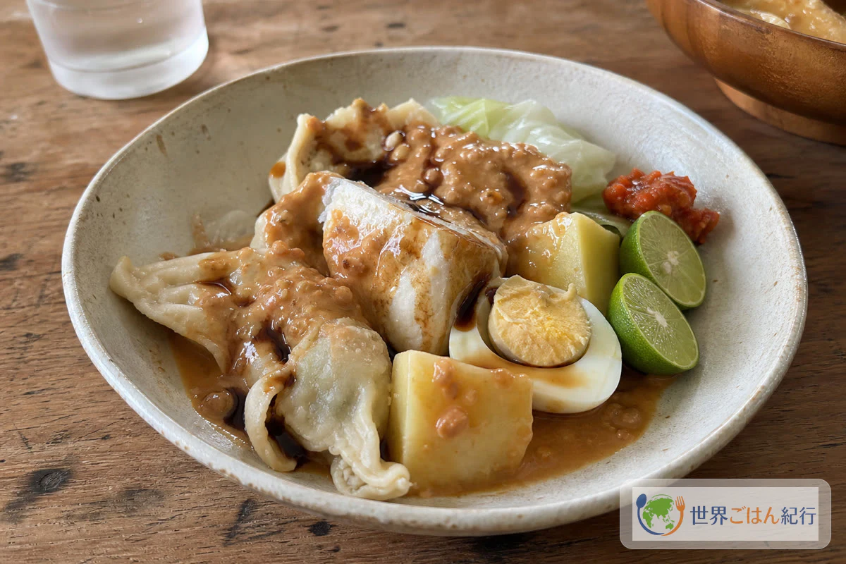 蒸した魚団子、豆腐、キャベツ、じゃがいも、卵にピーナッツだれをかけたインドネシアのシオマイ