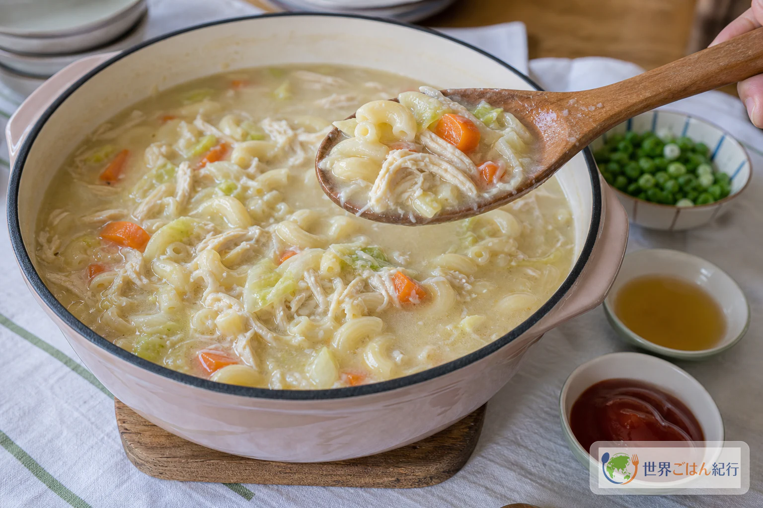 鍋ごと食卓に出したSopas。マカロニ、鶏肉、キャベツ、にんじんが白いスープに入り、横にパティスと青ねぎを置いている
