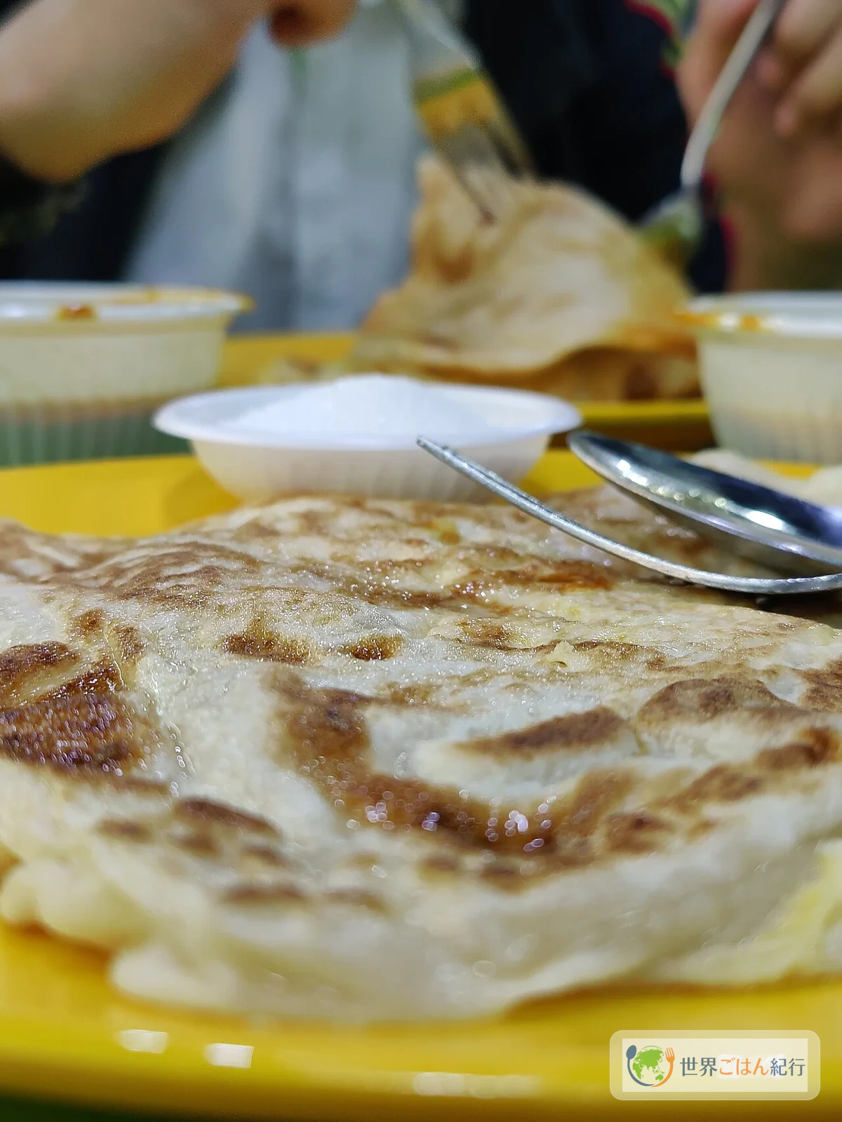 マレーシアのフードコートでロティ・チャナイを食べている風景